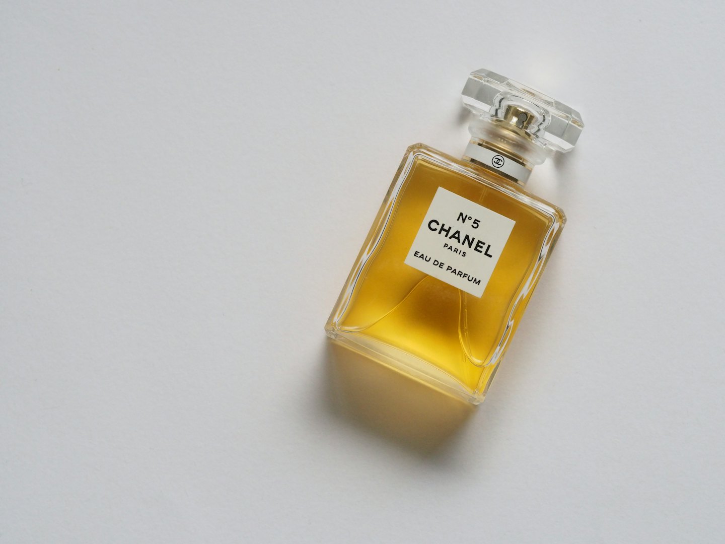 Bernsteinfarbene Parfümflasche mit facettiertem Verschluss auf weißem Hintergrund.