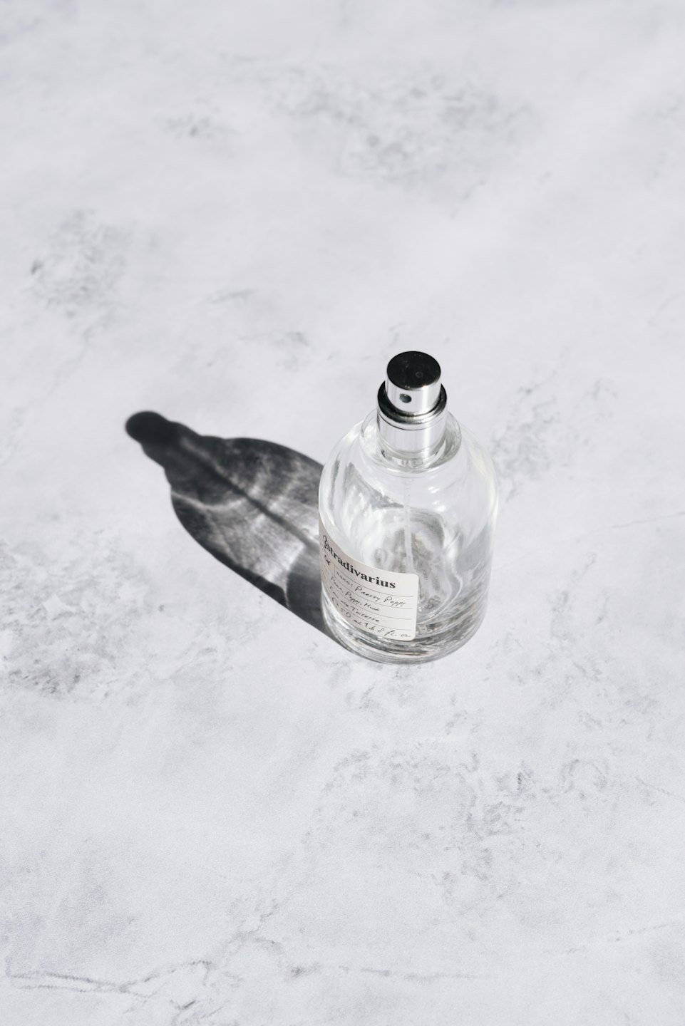 Eine Parfümflasche mit silber-schwarzer Kappe auf Marmor.